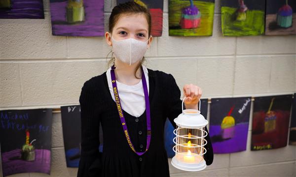 A girl holds up a lantern